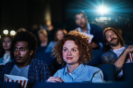Young diverse group of friends watching a movie together in the movie theater