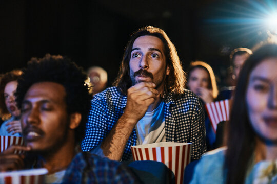 Young diverse group of friends watching a movie together in the movie theater