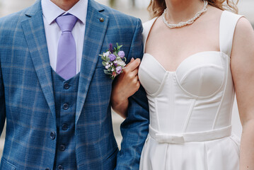 groom hugs bride outdoors on wedding photosession, close-up view of torsos, love and family concept