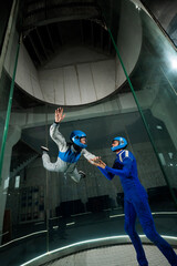 A male instructor teaches a woman how to fly in a wind tunnel. Free fall simulator.