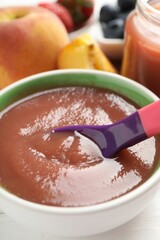 Baby food. Eating tasty puree with spoon at white wooden table, closeup