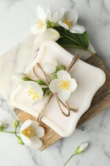 Soap bar and jasmine flowers on white marble table, flat lay