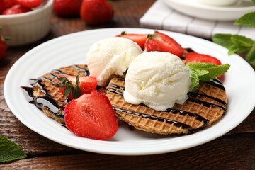 Tasty Dutch waffles (stroopwafels) with strawberries, ice cream and chocolate sauce on wooden table, closeup