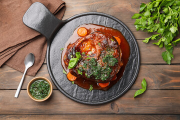 Traditional ossobuco dish with beef steak and sauce served on wooden table, flat lay