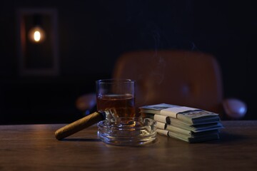 Ashtray with cigar, money and whiskey on wooden table in mafia boss office
