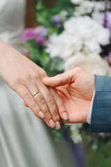 close-up view of couple holding hands, bride and groom, young beautiful caucasian man and woman take each other hands, walk on pathway in park in summer, love and family concept, selective focus