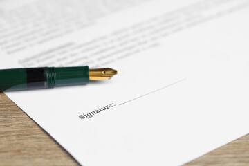 Notary document and fountain pen on wooden table, closeup