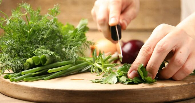 Woman cutting cilantro and other different herbs at table, closeup