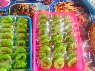 Eye-Catching Green Pandan Cake Rolls on Colorful Trays, Delicious pandan cake rolls presented in...