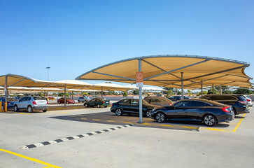 Modern open-air parking lot in Australia featuring tensile fabric shade structures over parked vehicles. Cars aligned under sun protection canopies. Concept of heat reduction and urban infrastructure.
