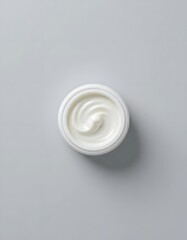 Aerial view of a white jar filled with swirling cream against a light gray background studio shot