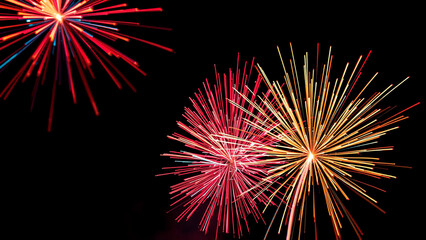 Fototapeta premium Fireworks exploding in the night sky with red and gold colors creating a festive atmosphere scene