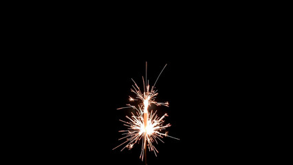 Obraz premium Close up shot of a single sparkler emitting bright sparks against a dark black background at night
