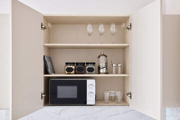 A Modern Kitchen Cupboard that features a Microwave along with elegant Glassware storage