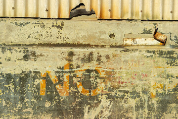 Distressed urban wall with faded lettering and rusted metal elements
