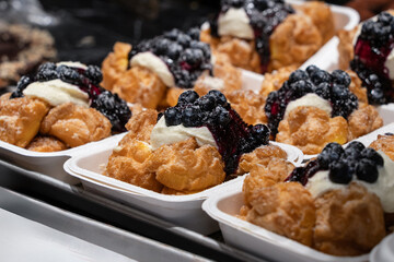 Fresh pastries in the bakery shop. Baked choux cream filled with cream and fresh blueberries.