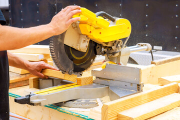 Carpenter person expertly uses miter saw to cut wooden boards under works day