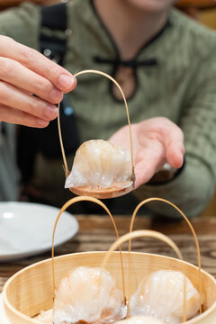Hand holding dim sum called Hakau, dumplings made from shrimp and meat is a traditional Chinese food.