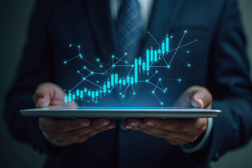 Businessman holding tablet with stock finance candlestick bar chart graph blue glowing floating