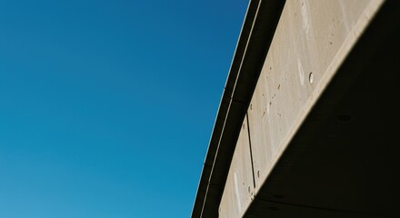 A low-angle view of a bridge's underside against a vibrant blue sky.  Modern concrete structure