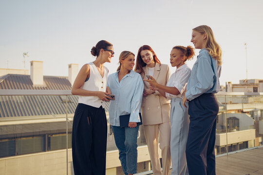 A group of diverse women are engaging in an enjoyable and lively conversation on a rooftop deck