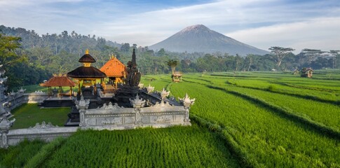 A scenic view of a Balinese temple in Abang, Bali, Indonesia, surrounded by lush green rice...