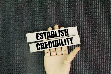 Man holding paper with the words ESTABLISH CREDIBILITY. the concept of credibility.demonstrating to...