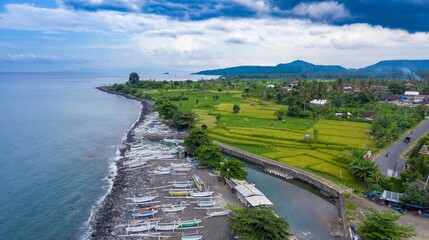 Aerial view of traditional fishing boats lining the black sand beach in Ujung, Bali, Indonesia. The...