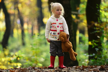 Alone child walking in autumn forest. Lonely girl in autumn woods. Kid walking alone with autumn leaves. Alone child in fall foliage. Portrait of lonely kid. Girl standing alone in forest. Lonely girl