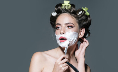 Funny woman shave beard with razors. Beauty woman shaving foam on face. Attractive girl is having a...