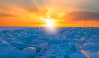 Beautiful winter landscape of frozen Lake Baikal at sunrise - Snowy ice hummocks with transparent...