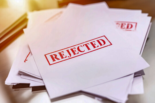 Stack of rejected documents with red REJECTED stamp, symbolizing failure and denial in business contexts.