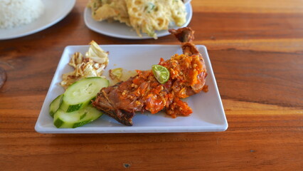 Delicious Indonesian Fried Chicken with Spicy Sauce, Cucumber, and Cabbage.
