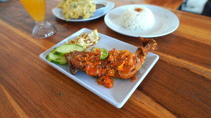 Delicious Indonesian Meal of Fried Chicken, Rice, and Vegetables on a Wooden Table