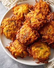 Golden-brown vegetable fritters served on a white plate, garnished and ready to enjoy