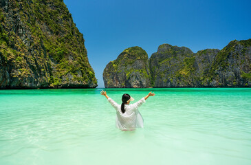 asian child summer or kid girl raising arms in clear green sea water and blue sky to happy on maya bay clean beach and mountain island for tourist vacation travel on holiday relax at krabi in thailand