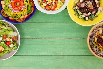 Various fresh salad on green wooden table