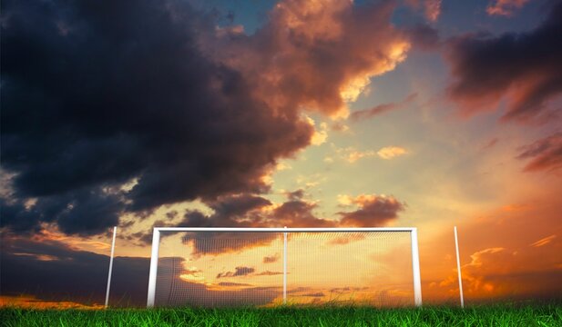 Fototapeta Football goal under orange cloudy sky