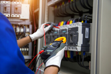 Electrical service technician use electricity measuring tools equipment checking electric current circuit breaker terminal panel and cable wiring main power distribution board for maintenance system.
