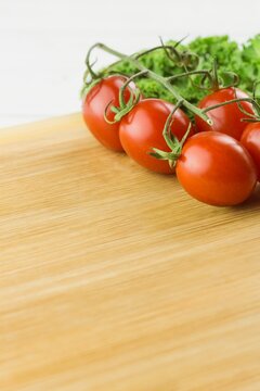 Fototapeta Tomatoes and parsley on chopping board against white background