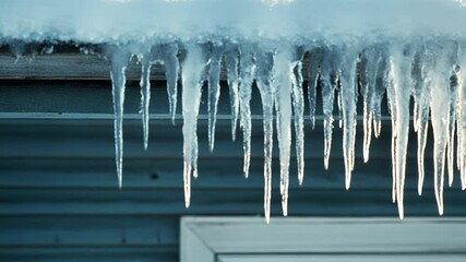 Sharp icicles hanging from roof covered with snow in winter - Powered by Adobe