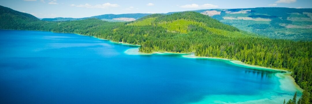 Fototapeta Expansive blue lake is being shown in flat design, with evergreen trees, hills and clouds