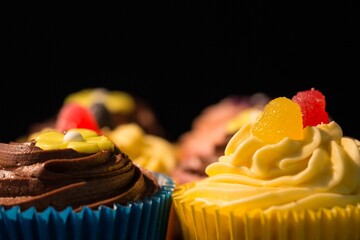 Flat illustration is featuring cupcakes in colorful liners with buttercream swirls and gumdrops