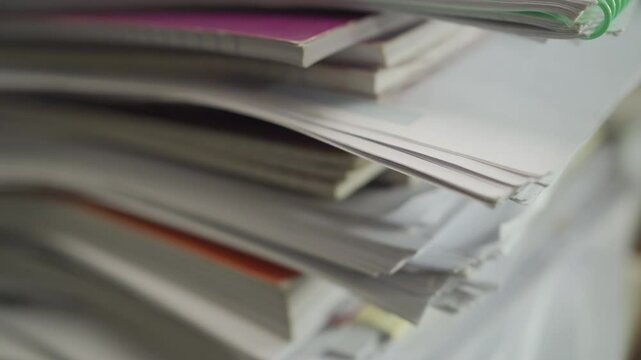 Observe a close-up of disorganized lecture sheets or office documents, piled high