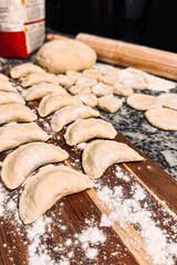 Homemade dumplings preparation on wooden board with rolling pin