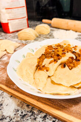 Homemade boiled dumplings with fried onions in rustic kitchen setting

