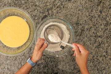 Overhead View of Hands Sifting Flour with Hand Crank Sifter for Baking