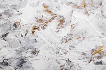 Putty white paste mixed with black ink, abstract close up detail of spatula strokes on golden paint...