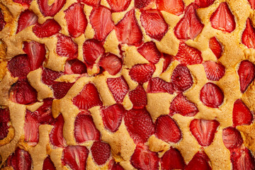 Cooked   sponge cake with strawberry slices, baking process, abstract backdrop
