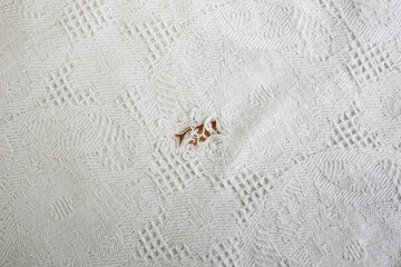 Ripped hole in a white textured white fabric table cloth, abstract backdrop